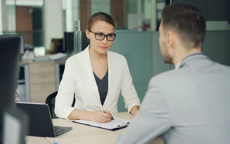 Two people sitting across a desk in an office meeting