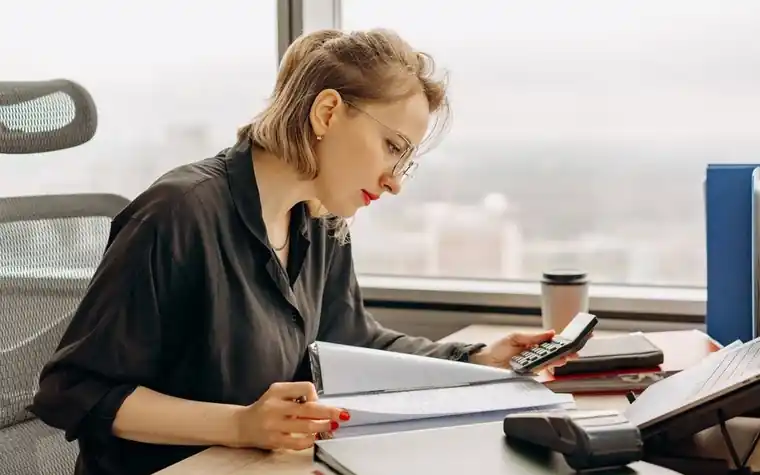 책상에서 서류와 계산기로 금액을 확인하는 모습