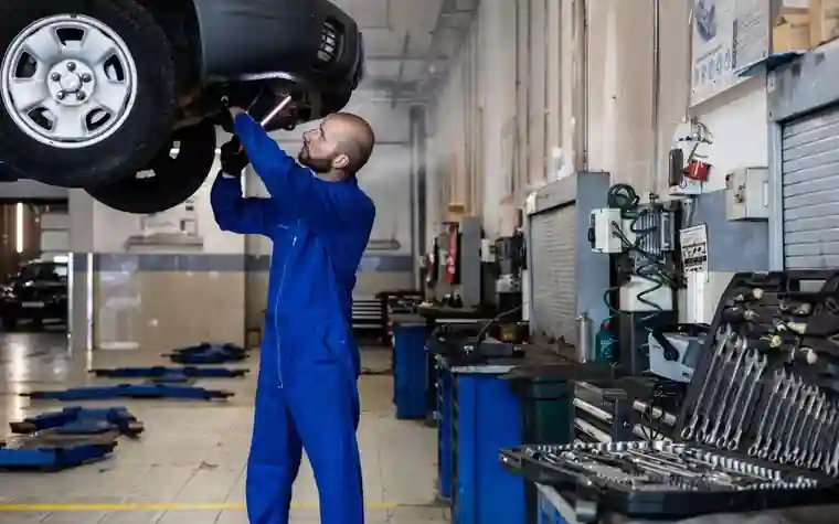 A mechanic inspecting the underside of a car in a garage